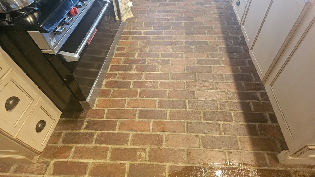 Dirty brick and grouted kitchen floor before cleaning