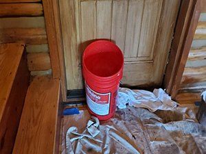 bucket catching water leak in log cabin