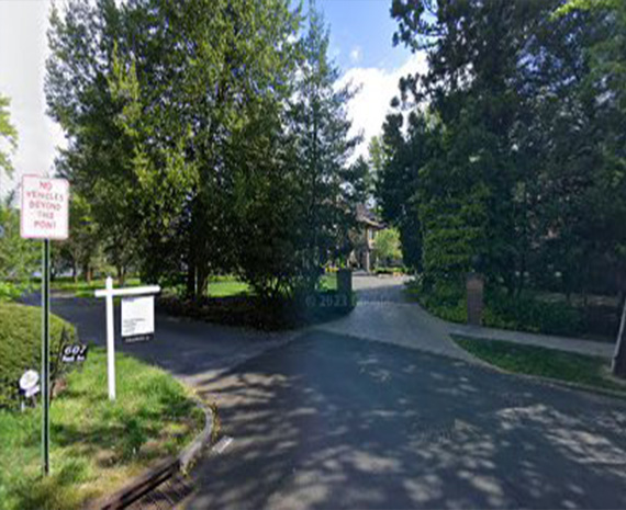 Tree-lined campus entrance with a 'No bicycles beyond this point' sign on the left side.