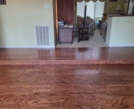Refinished engineered hardwood family room floor and long wood riser blended to match.