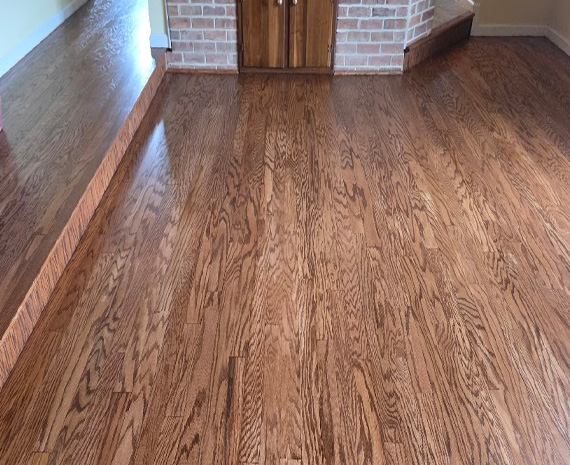 Refinished engineered wood family room with aquarium trim stained and installed to match floor.