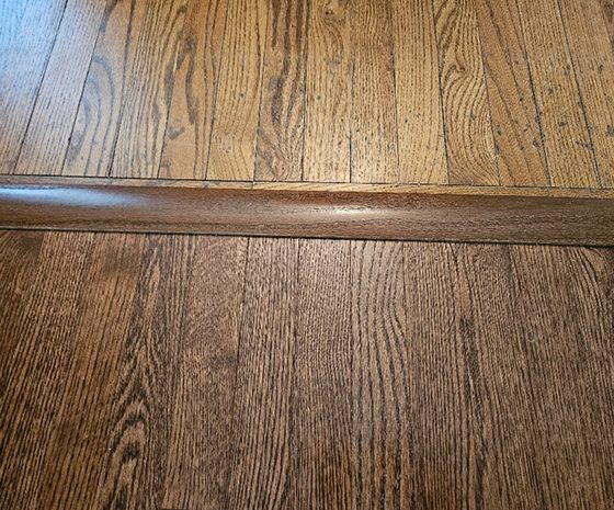 Raised hardwood transition between adjoining floors before refinishing in Tabernacle, NJ.