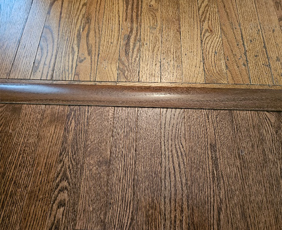 Raised hardwood transition between adjoining floors before refinishing in Tabernacle, NJ.